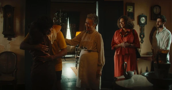 一家人在 A Herança 的老房子里热情拥抱，长辈们面带微笑地注视着