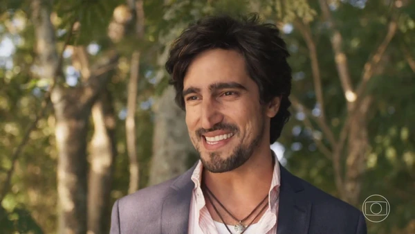 A male actor in Mar do Sertão smiling amidst lush trees.