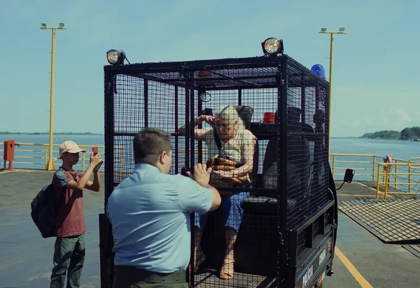 Elderly woman in cage in "O Último Azul" by the water.