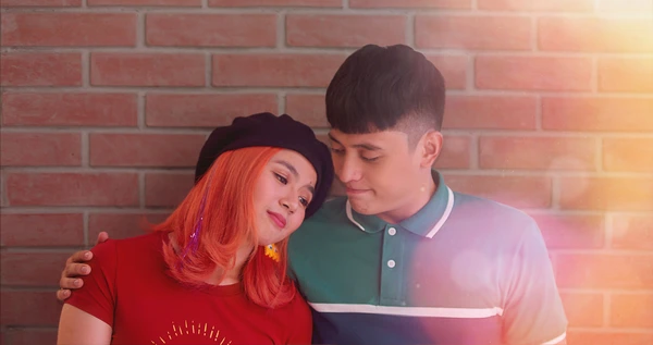 “《Conexões Perdidas》中的浪漫场景，一对情侣靠在砖墙上。”