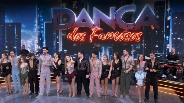 Contestants of Dança dos Famosos stand on stage under the show's illuminated logo.