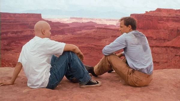 Two men look over a cliff in "Na Trilha do Sol".